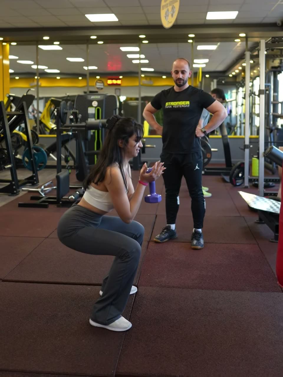 Eğitmen eşliğinde squat yapan üye